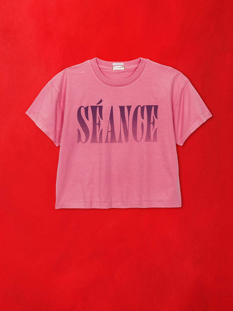 A flat image of a pink graphic tee against a red background.