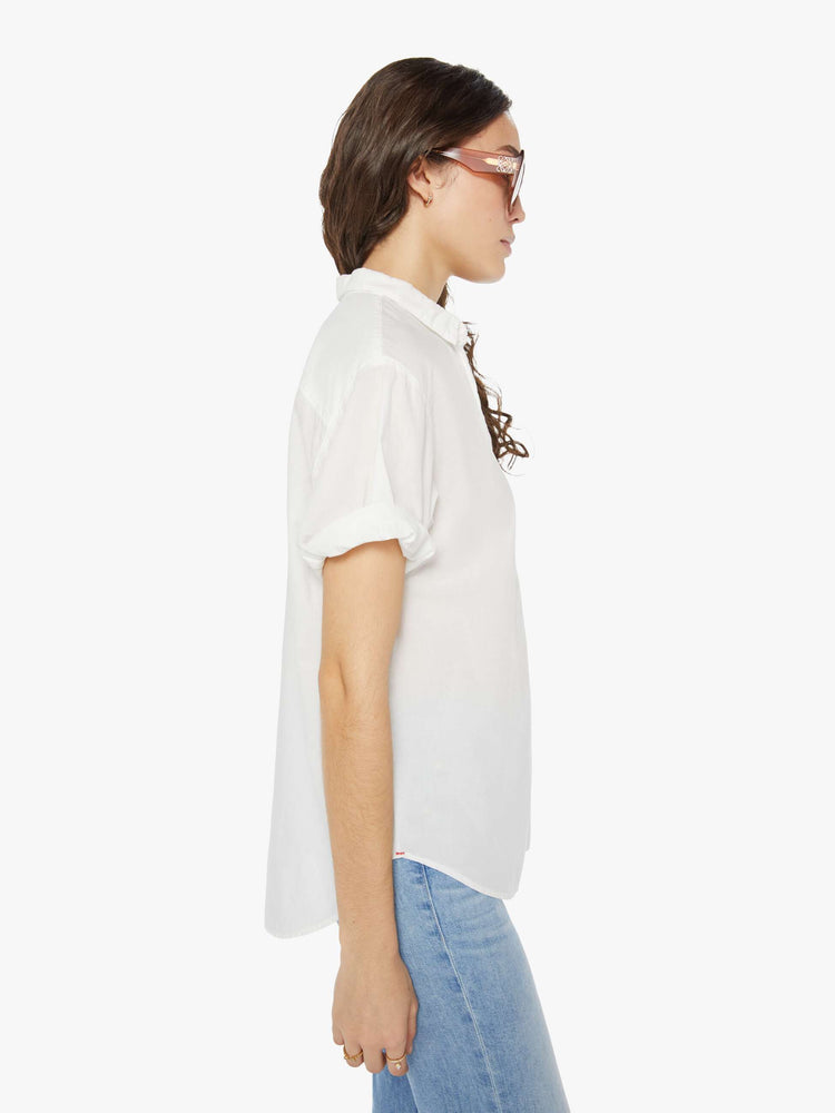 Side view of a woman wearing a white short sleeve button up shirt.