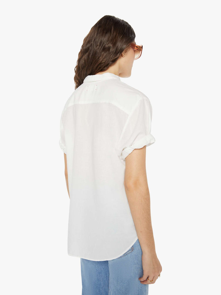 Back view of a woman wearing a white short sleeve button up shirt.