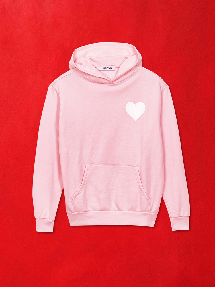 A flat image of a light pink sweatshirt hoodie with a white heart, against a red background.