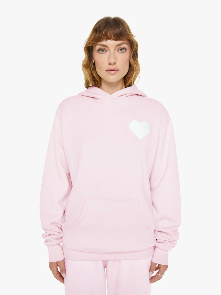 Front view of a woman in a pink with white heart sweatshirt with a front patch pocket and a loose, comfortable fit.