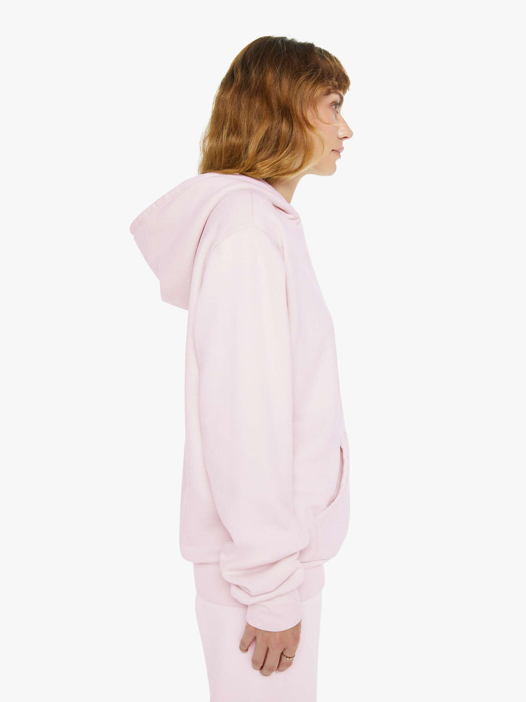 Side view of a woman in a pink with white heart sweatshirt with a front patch pocket and a loose, comfortable fit.