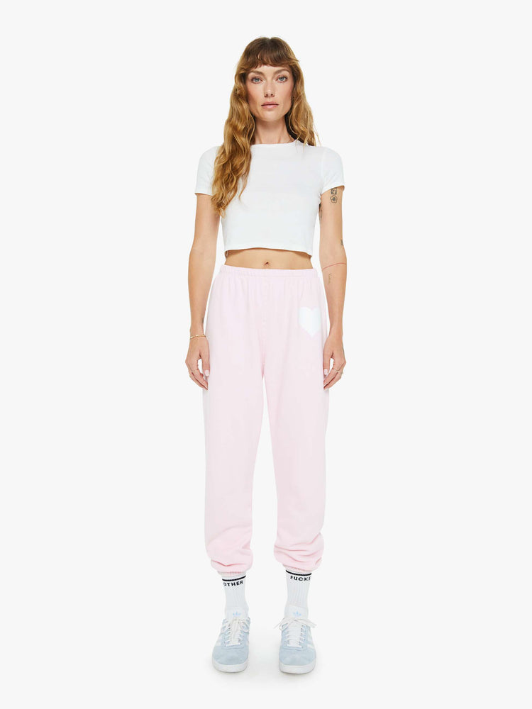 Front view of a woman's pink sweatpant with a white heart on the hip and an elastic waist and cuffs for a loose, comfortable fit.