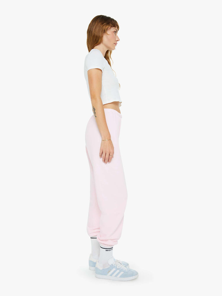 Side view of a woman's pink sweatpant with a white heart on the hip and an elastic waist and cuffs for a loose, comfortable fit.