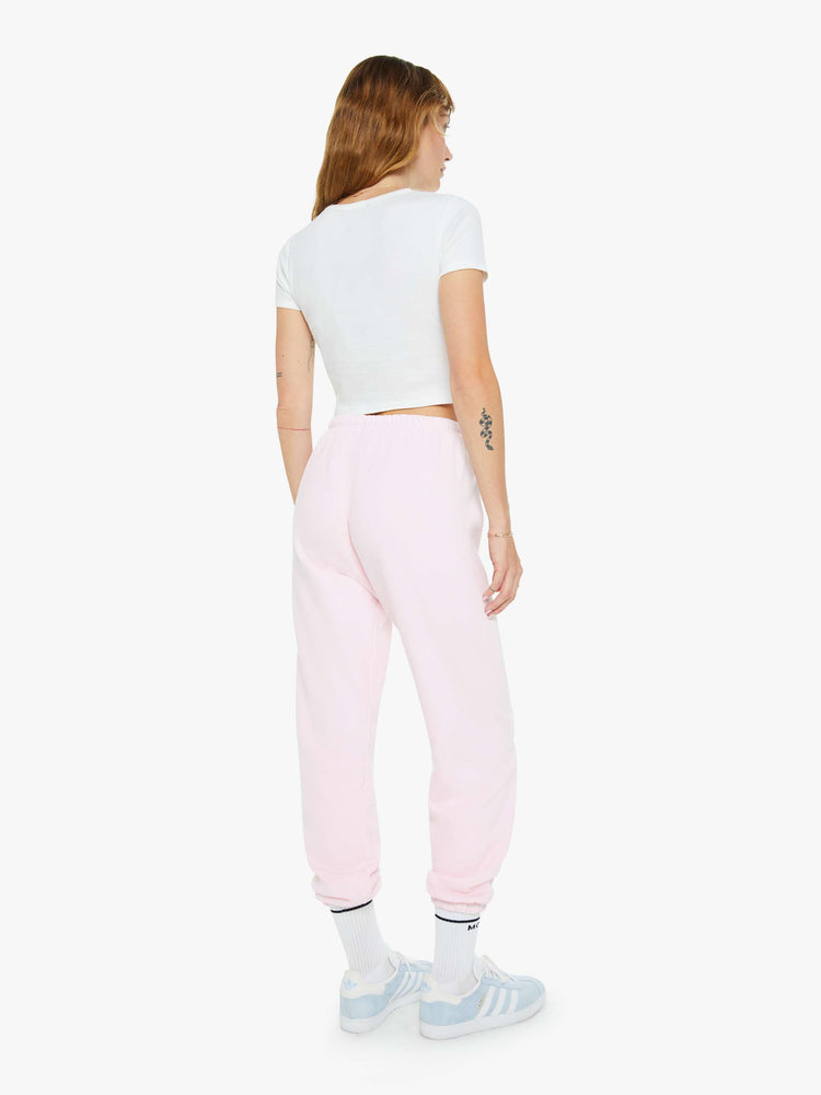 Back view of a woman's pink sweatpant with a white heart on the hip and an elastic waist and cuffs for a loose, comfortable fit.