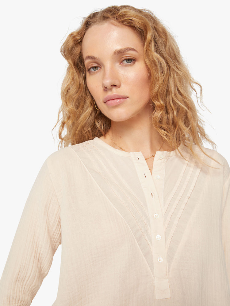 Close up view of a woman buttoned vneck, eyelet details shirt in a oat hue.