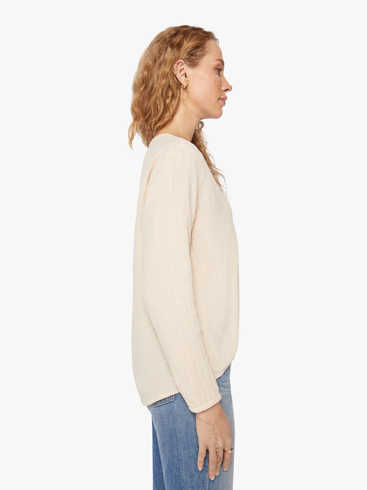 Side view of a woman buttoned vneck, eyelet details shirt in a oat hue.