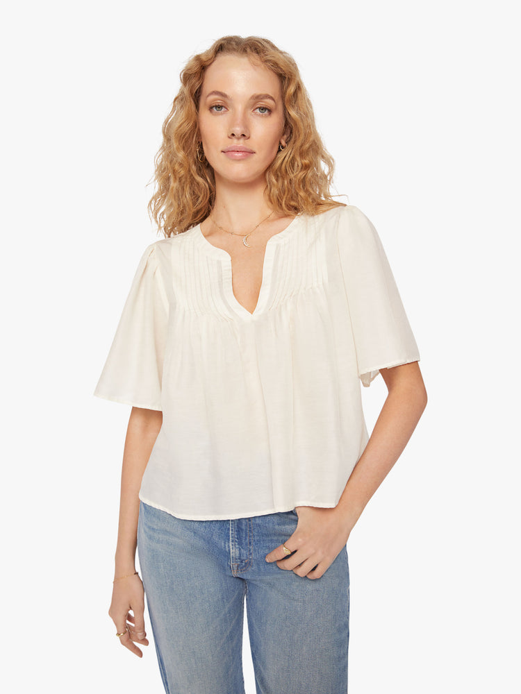 Front view of a woman pearly-white hue blouse with a vneck, short, boxy sleeves and a cropped hem.