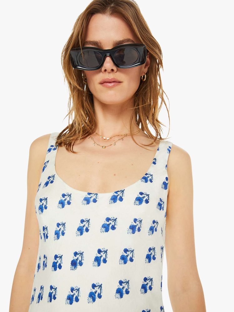 Close up view of a woman slip dress in white with a blue porcelain-inspired print, and features a scoop neck, narrow fit and an ankle-length hem.