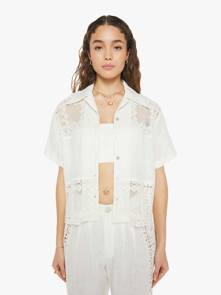 Front view of a woman short sleeve button up in off-white, and features a buttoned V-neck, slightly dropped shoulders and a boxy fit.