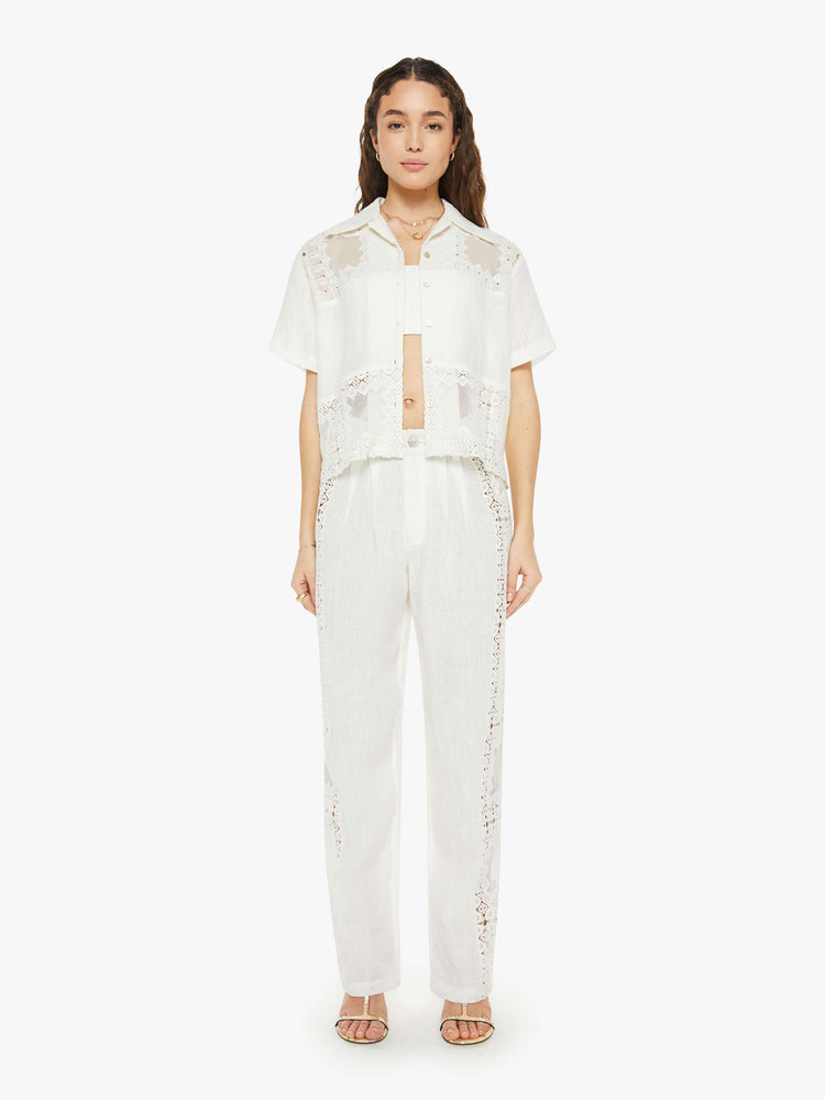 Full body view of a woman short sleeve button up in off-white, and features a buttoned V-neck, slightly dropped shoulders and a boxy fit.