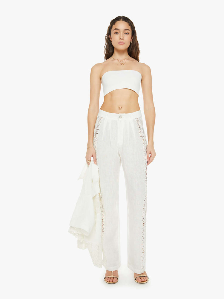 Front view of a woman linen pants in off-white, and feature a loose straight leg, ankle-length inseam and patchwork details down the side of each leg.