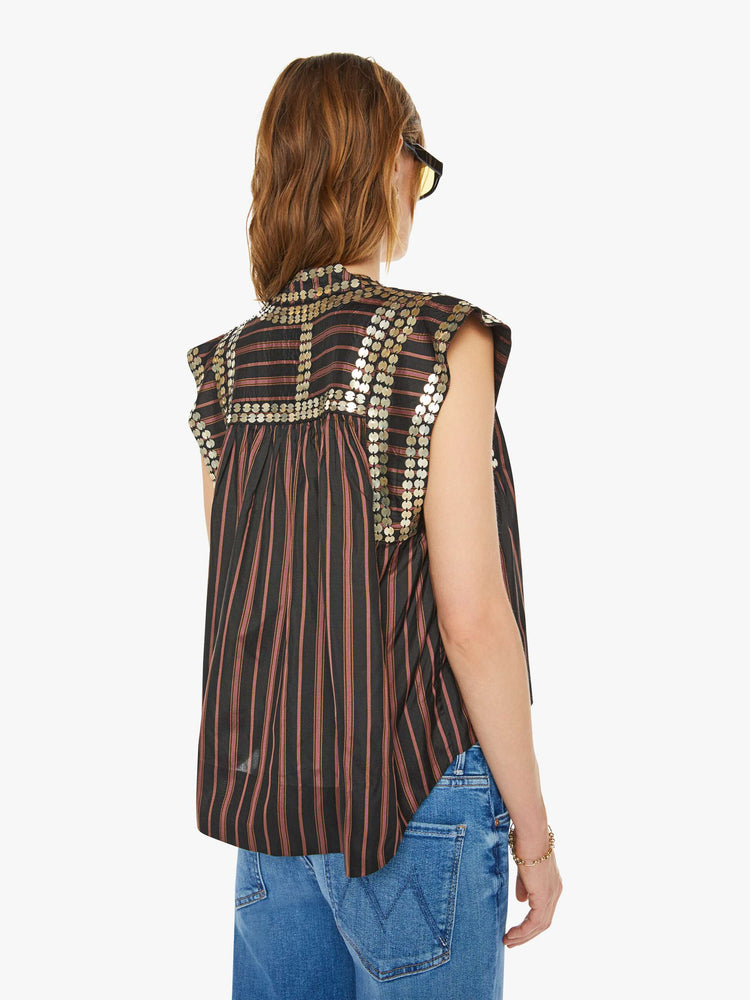 Back view of a woman brown with vertical black stripes in a scoop neck, structured short sleeves, a loose fit and coin embellishments throughout.