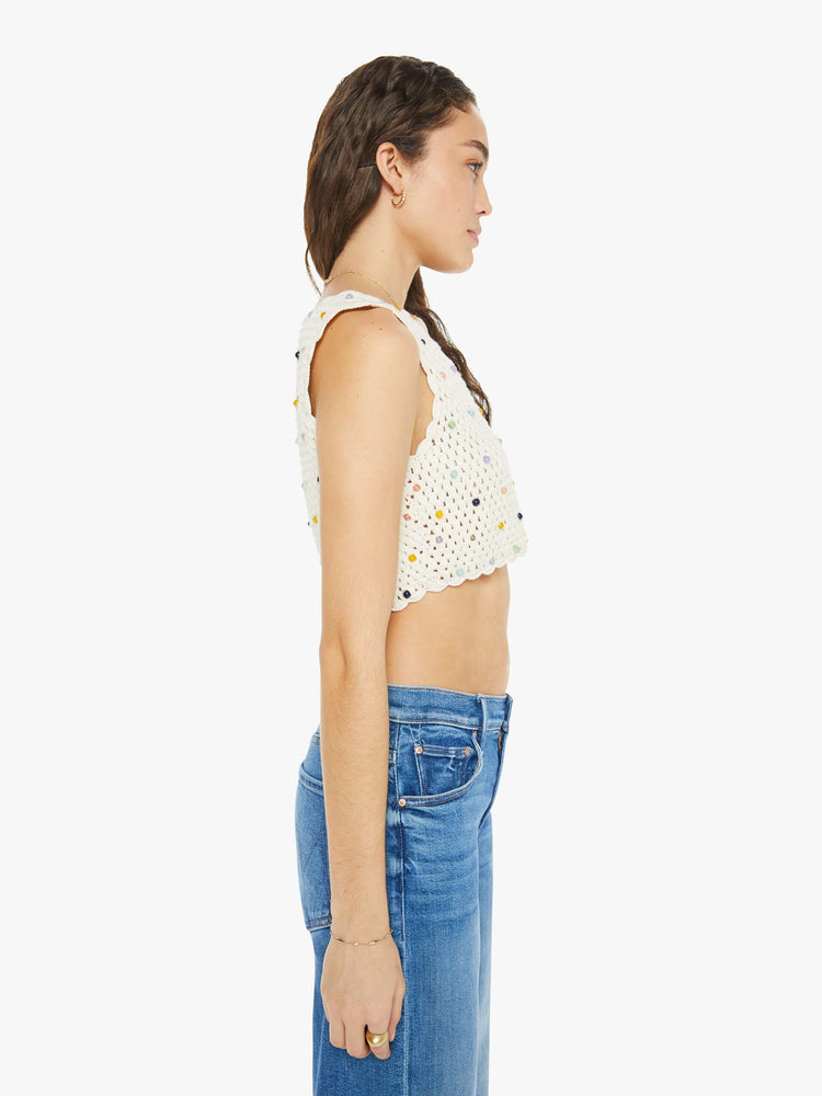 Side view of a sleeveless crochet top in ivory, and features a V-neck, buttons down the front, a cropped hem and bead embellishments throughout.