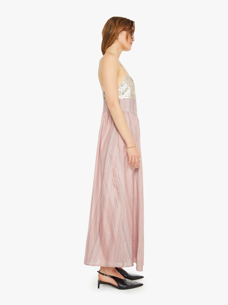 Side  view of a woman formal midi dress in mauve, and features a V-neck, thin spaghetti straps, a fitted bodice with coin embellishments, and a loose, flowy skirt that hits at the calf.