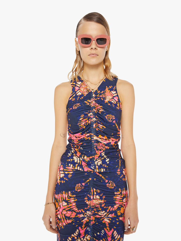 Front view of a woman in a deep navy with a warm-toned floral print, the sleeveless top features a high V-neck, a gathered seam down the front and a narrow fit.