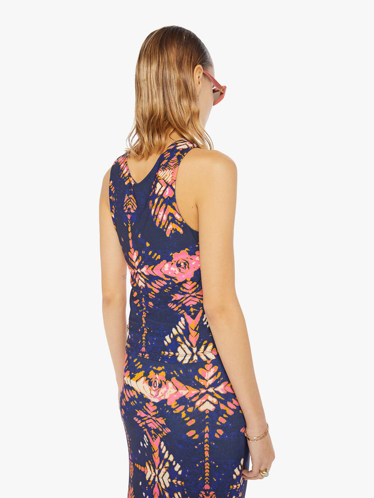 Back view of a woman in a deep navy with a warm-toned floral print, the sleeveless top features a high V-neck, a gathered seam down the front and a narrow fit.