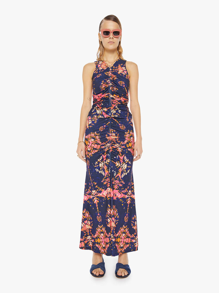 Full body view of a woman in a deep navy with a warm-toned floral print, the sleeveless top features a high V-neck, a gathered seam down the front and a narrow fit.