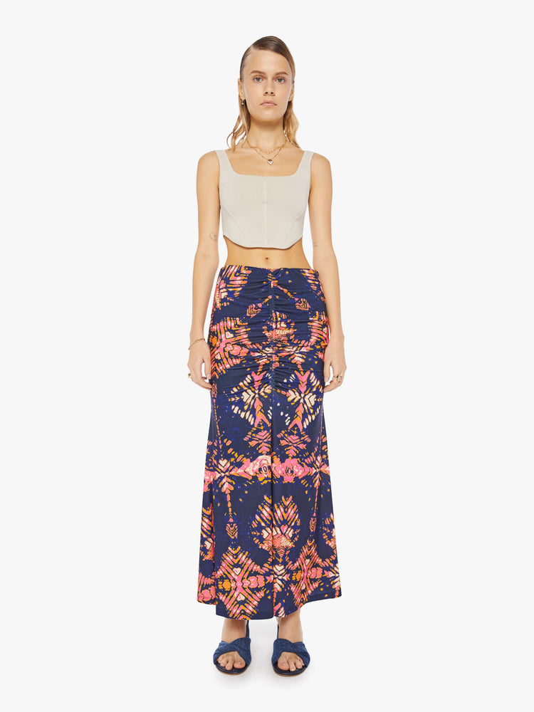 Front view of woman in a deep navy with a warm-toned floral print, the ankle-grazing skirt features a high rise, a gathered seam down the front and an A-line fit.