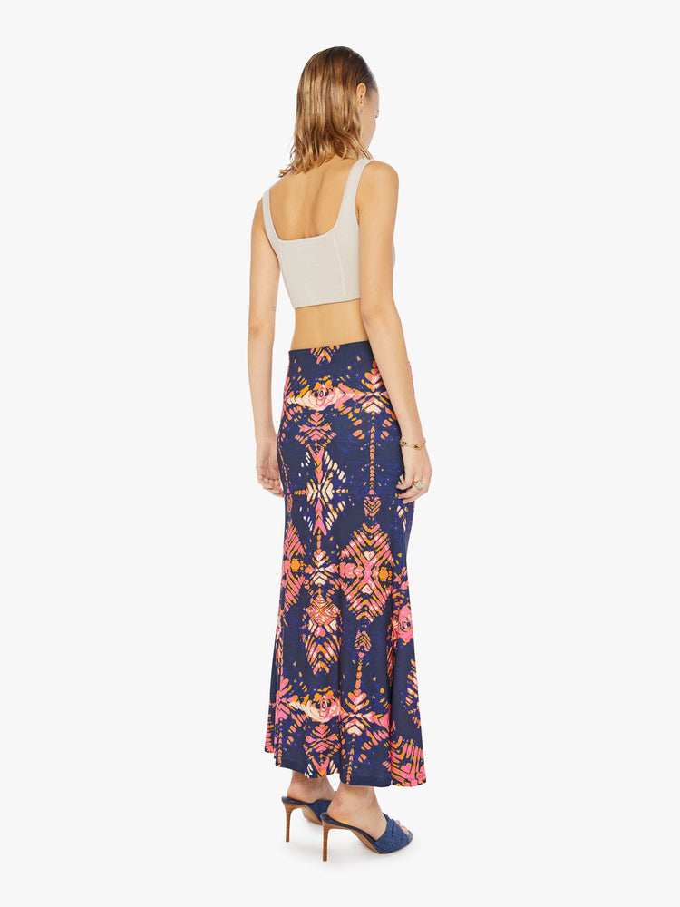 Back view of woman in a deep navy with a warm-toned floral print, the ankle-grazing skirt features a high rise, a gathered seam down the front and an A-line fit