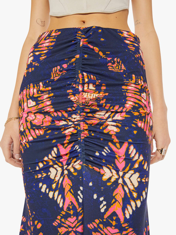 Waist close up view of woman in a deep navy with a warm-toned floral print, the ankle-grazing skirt features a high rise, a gathered seam down the front and an A-line fit