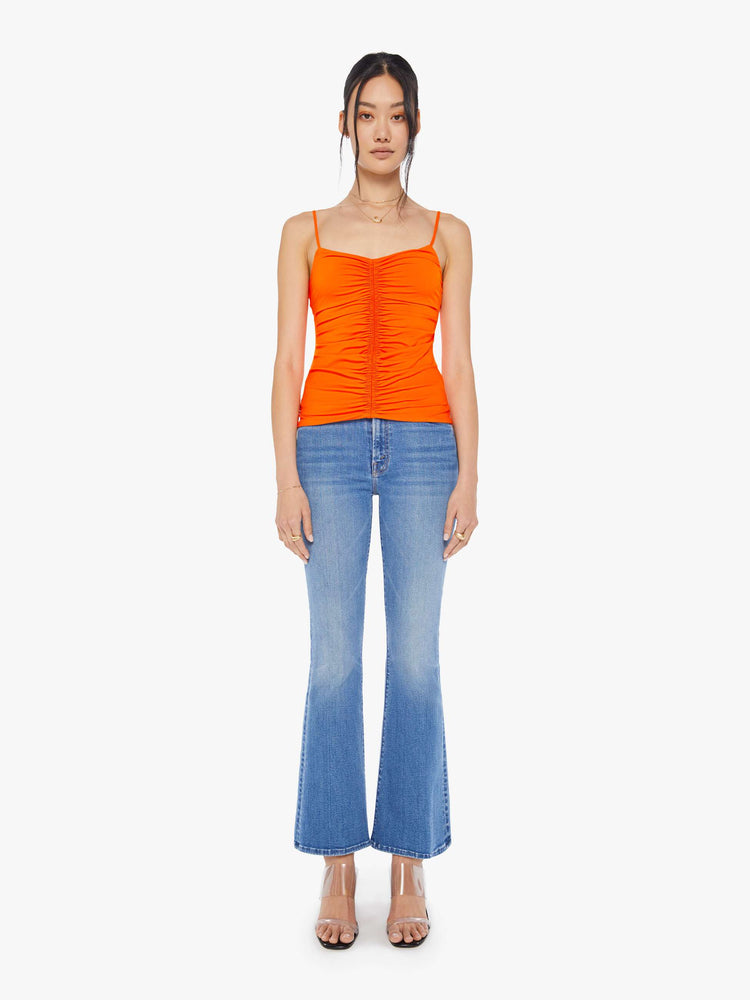 Full body view of a neon orange sleeveless top with a shallow V-neck, thin spaghetti straps, a gathered seam down the front and a narrow fit.