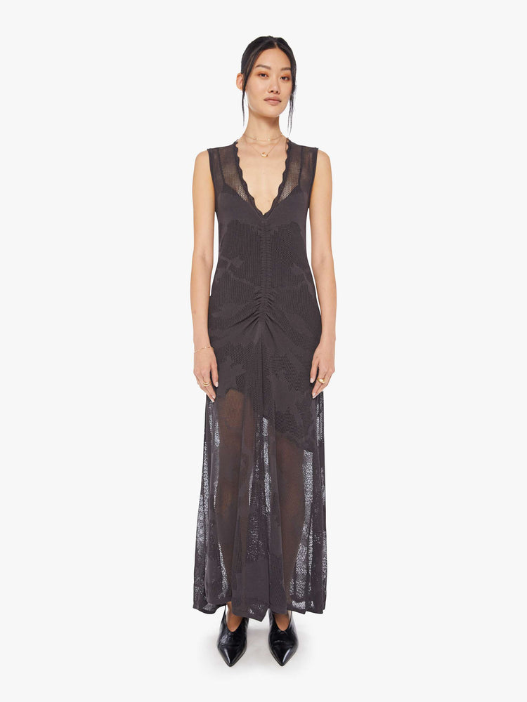 Front view of a woman black midi dress with a deep V-neck, a gathered seam down the front and a loose skirt with an ankle-grazing hem.