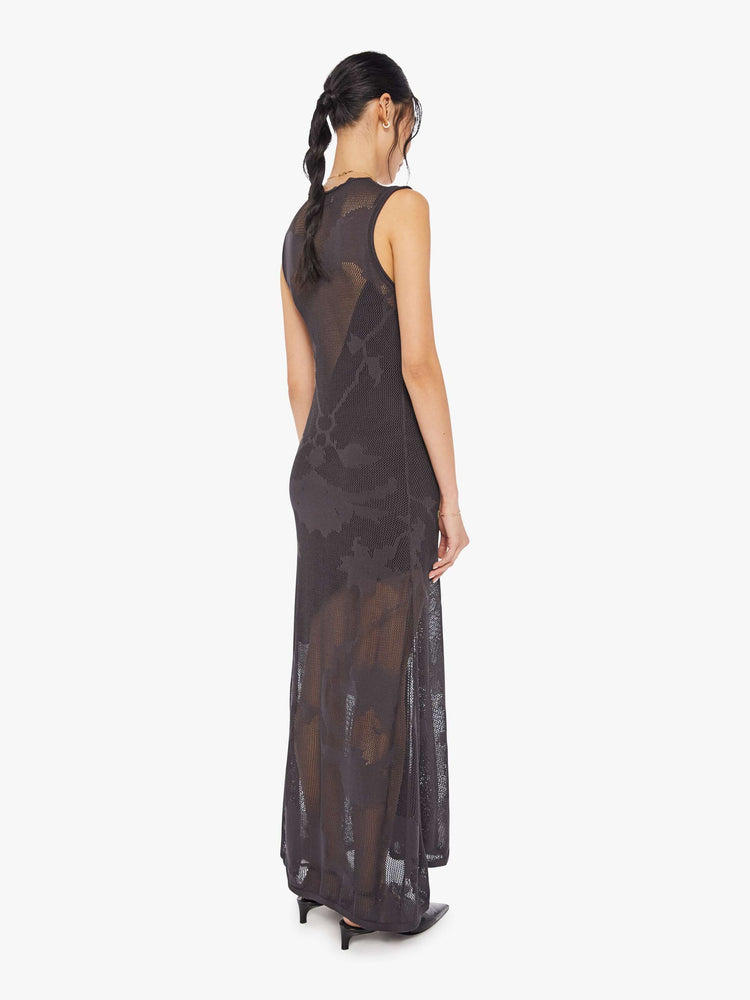 Back view of a woman black midi dress with a deep V-neck, a gathered seam down the front and a loose skirt with an ankle-grazing hem.