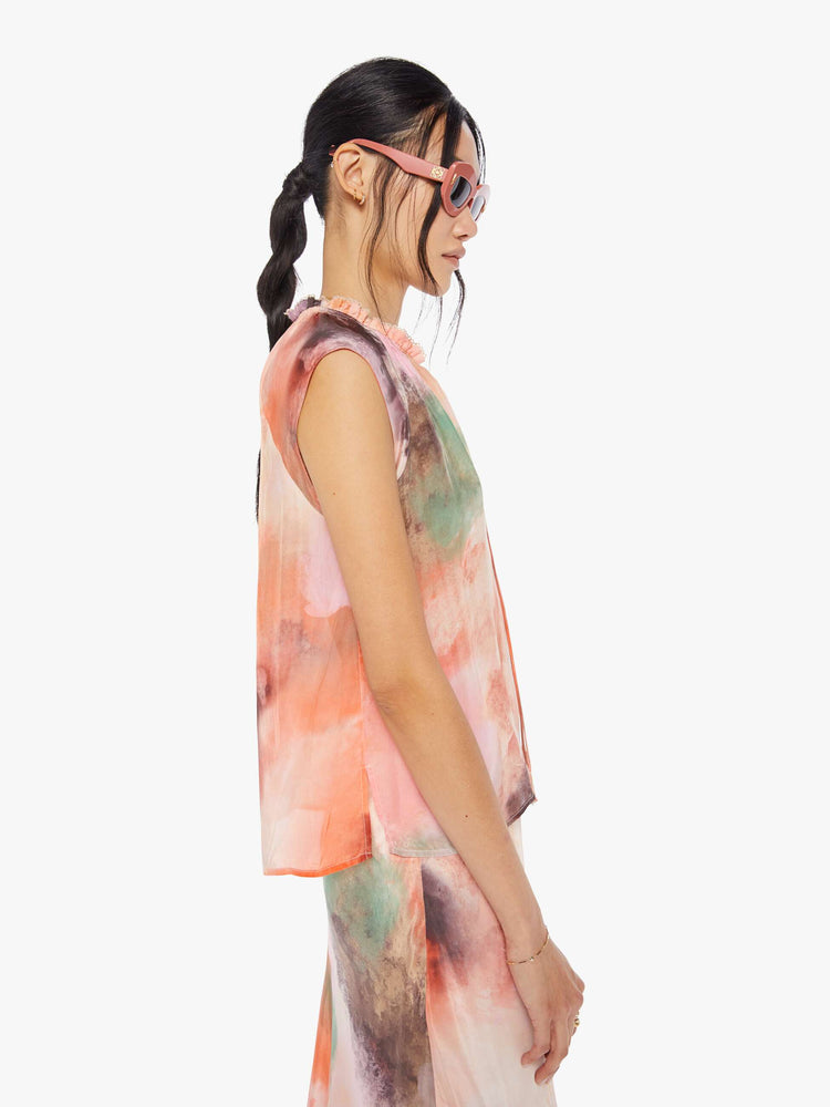 Side view of a watercolor inspired top with a V-neck with a ruffled collar that ties, super-short sleeves and a loose, flowy fit.