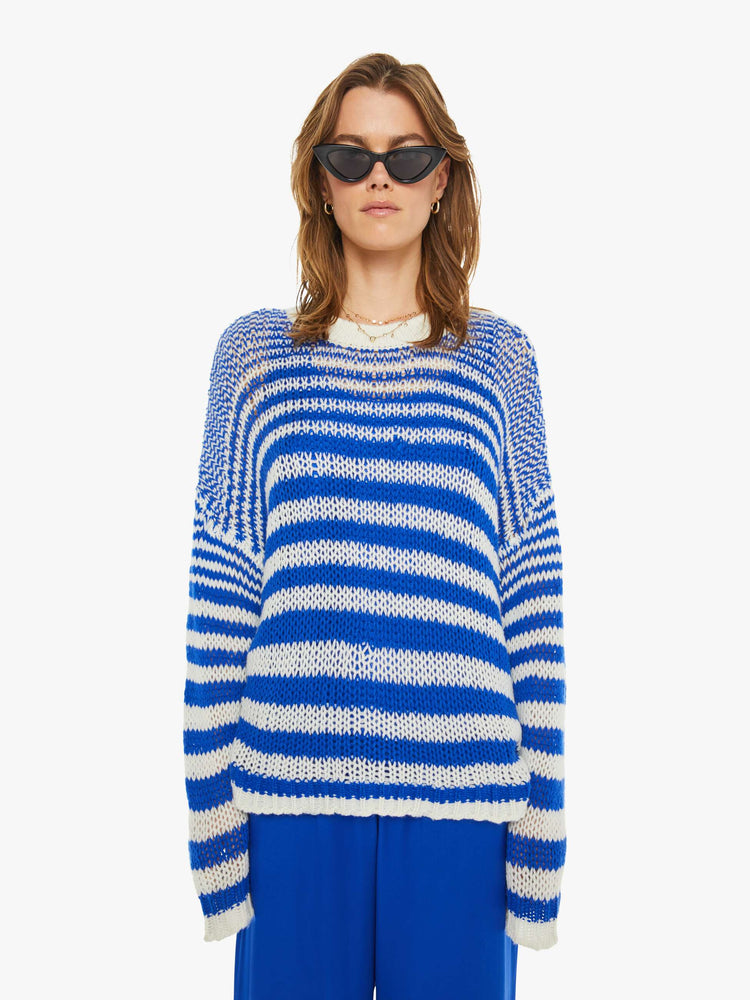 Front view of a woman in a blue and white striped knit crewneck with drop shoulders, long sleeves and an oversized fit.