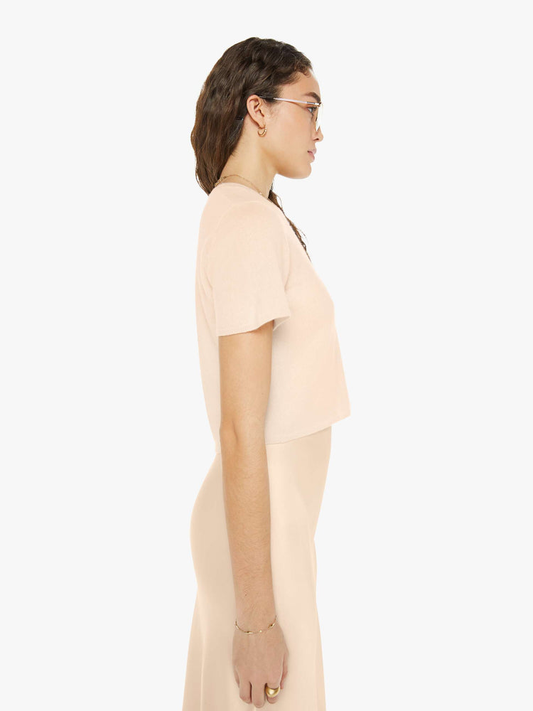 Side view of a woman wearing a peach cropped crew neck knit shirt.