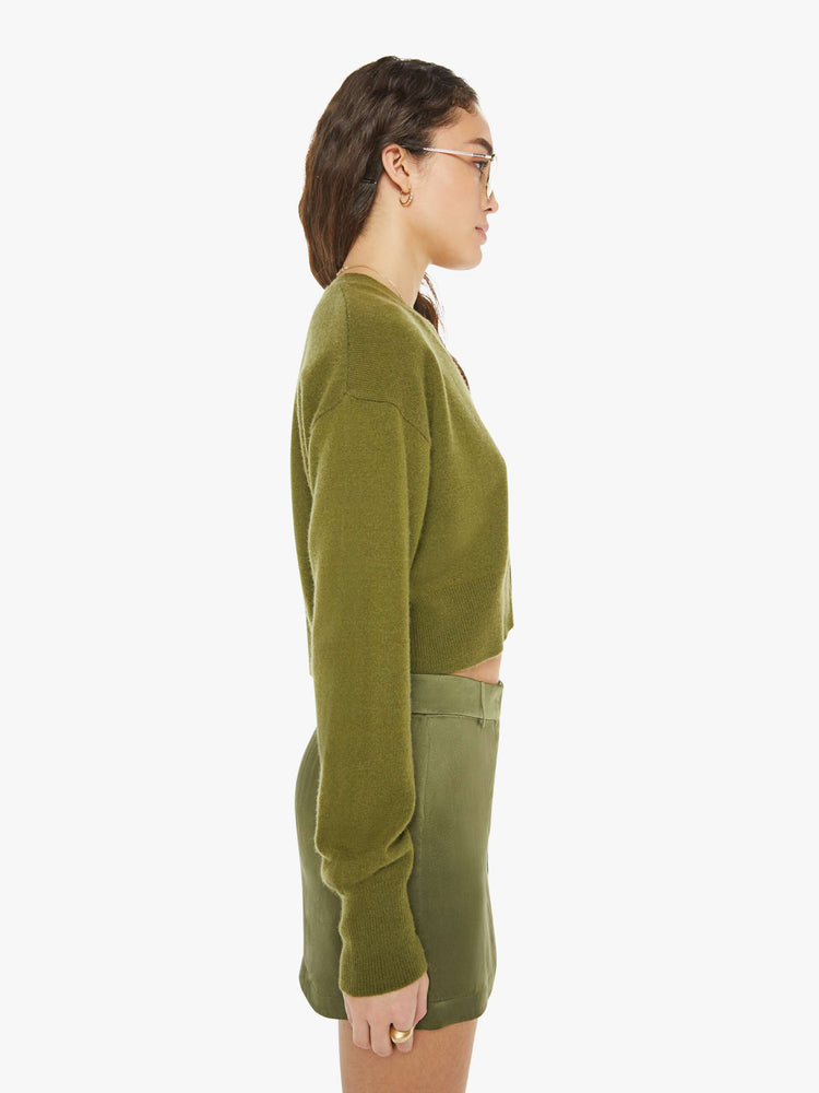 Side view of a woman in a green deep V-neck, drop shoulders, ribbed hems and a slightly cropped fit.