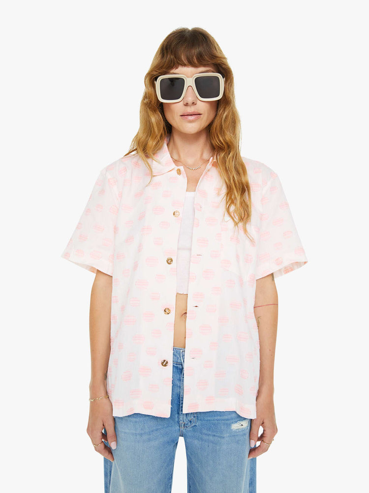 Front view of a woman wearing an white oversized short sleeve button down shirt with pink polka dots.