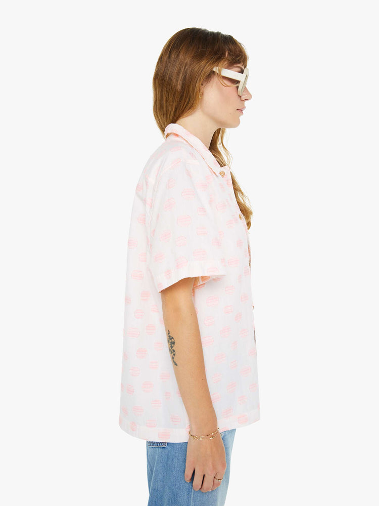 Side view of a woman wearing an white oversized short sleeve button down shirt with pink polka dots.