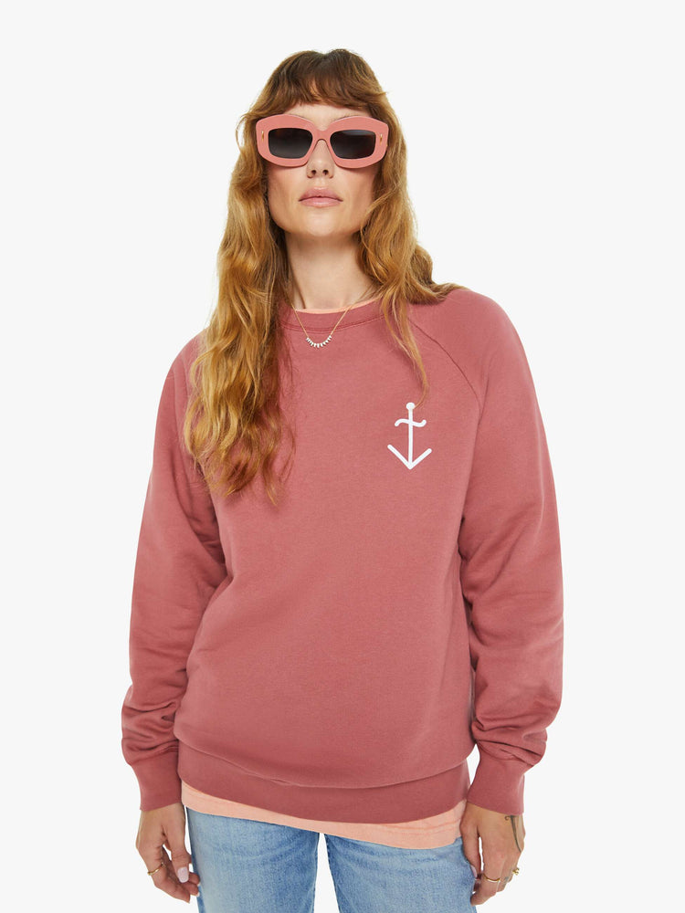 Front view of a woman in a faded brick sweatshirt with a relaxed shape with raglan sleeves and is decorated with a white anchor graphic on the chest.