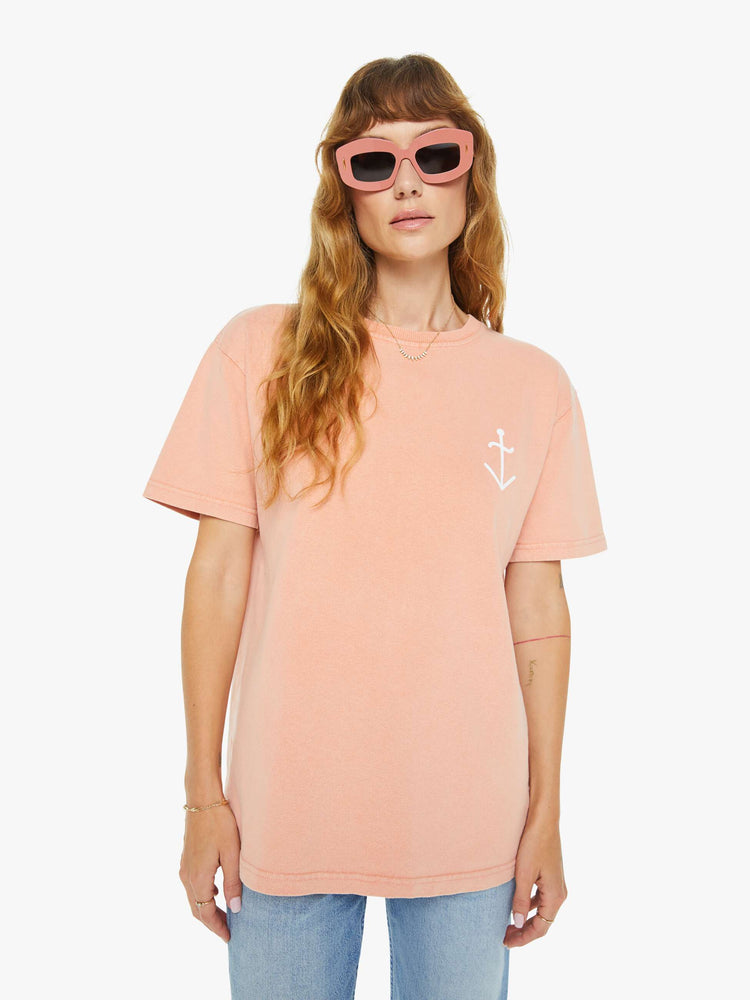 Front view of a woman light peach tee with a white anchor graphic on the chest, has a ribbed crewneck and a straight fit.