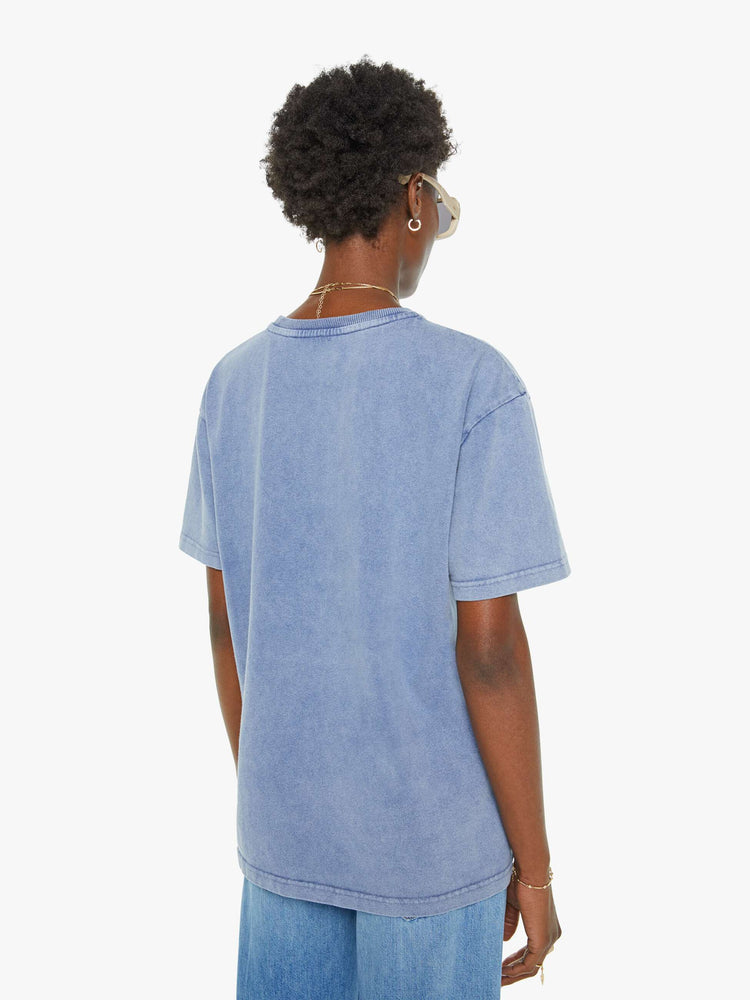 Back view of a woman in a faded blue with a white anchor graphic on the chest, has a ribbed crewneck and a straight fit.