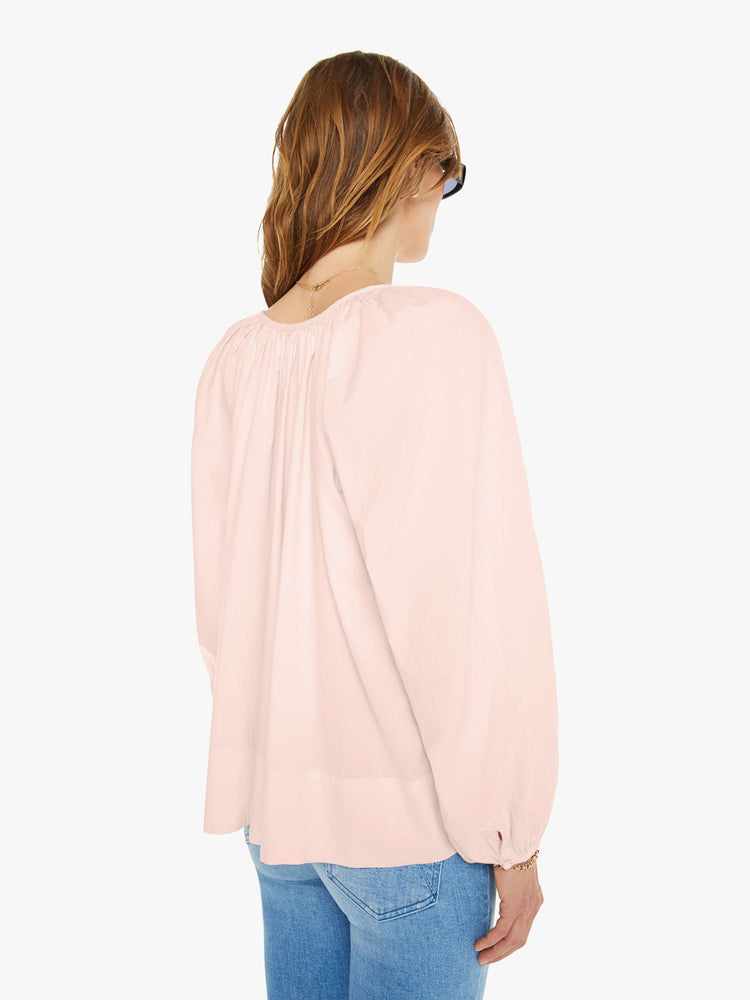 Back view of a woman in a pink blouse with a deep V-neck, long balloon sleeves, a thick hem and ruffles throughout for a loose, flowy fit.