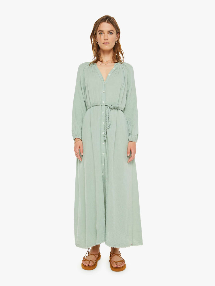 Front view of a woman maxi dress designed with a V-neck, long balloon sleeves, buttons down the front, a tied waist and ankle-grazing hem in a soft green gray.