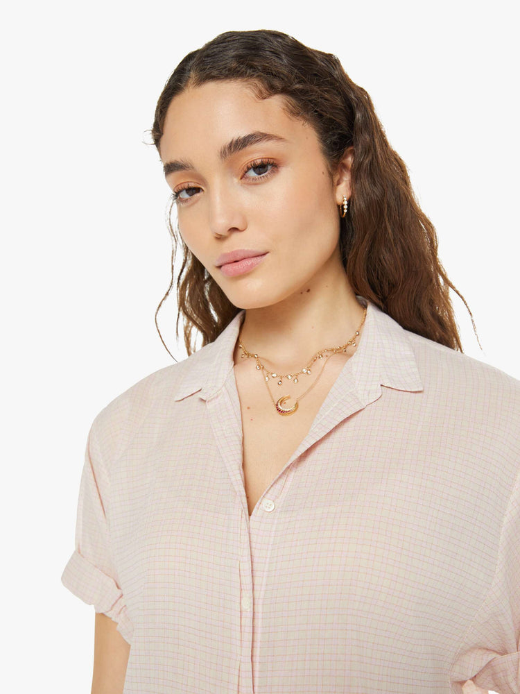 Close up view of a woman in a button down collared shirt in a rose-pink checkered print.