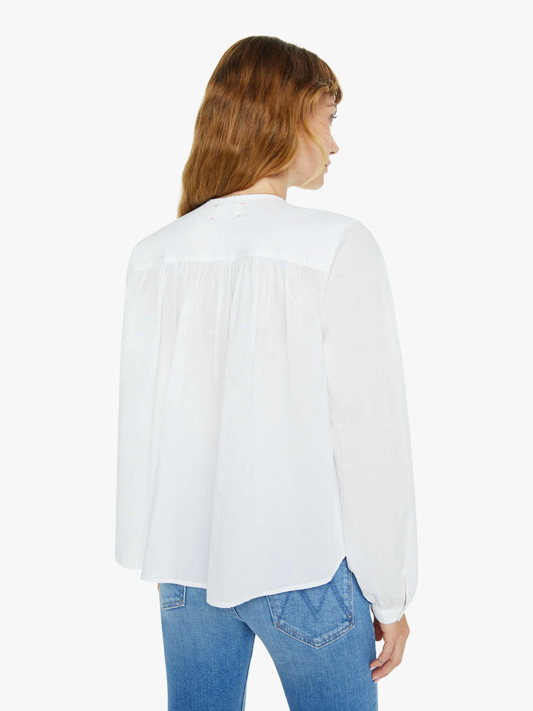 Back view of a woman white long sleeve buttoned V-neck, long balloon sleeves and has a loose, flowy fit.