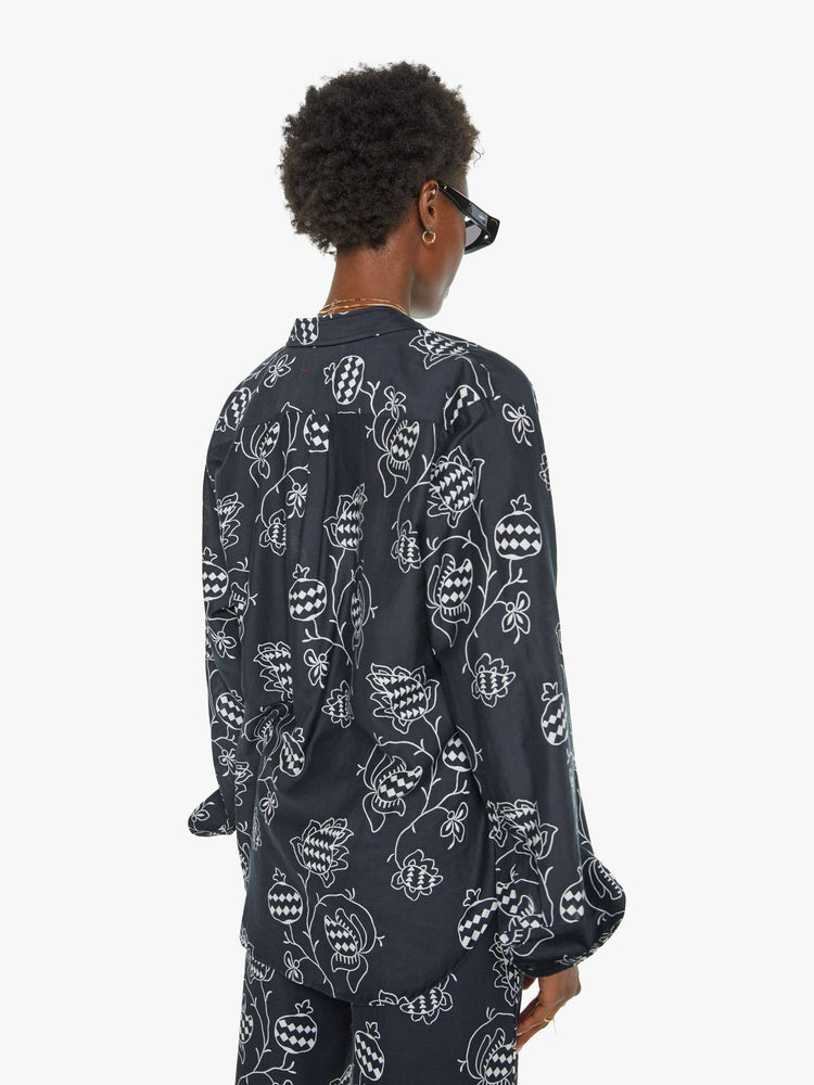 Back view of a woman in a black with a white floral print button down.