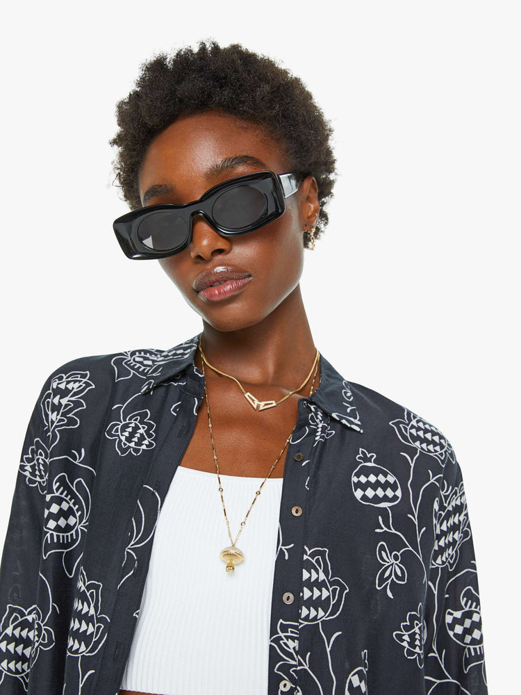 Close up view of a woman in a black with a white floral print button down.