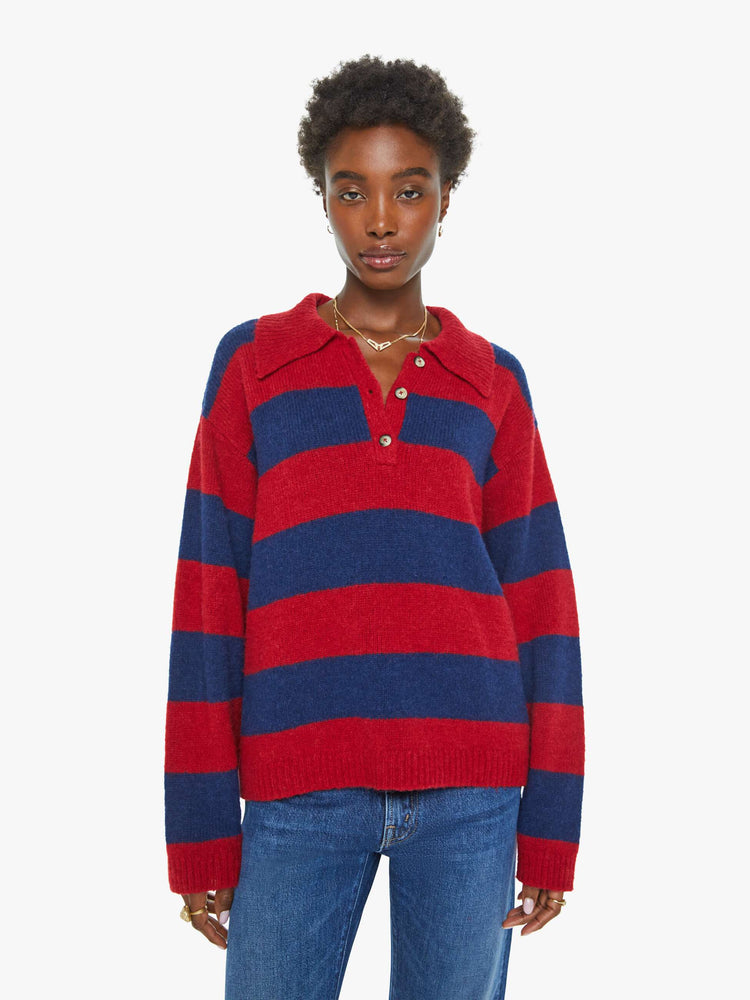 Front view of a woman in a blue and red sweater stripes drop shoulders, a buttoned V-neck, ribbed hems and a loose, boxy fit.