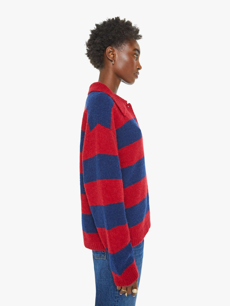 Side view of a woman in a blue and red sweater stripes drop shoulders, a buttoned V-neck, ribbed hems and a loose, boxy fit.