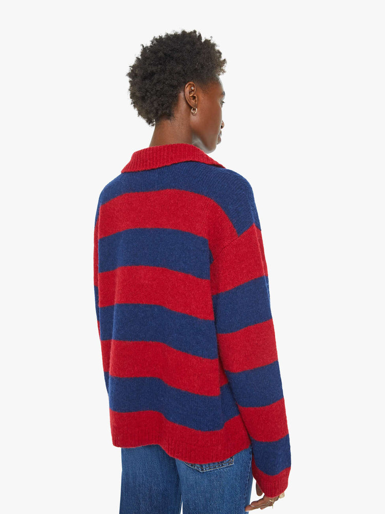 Back view of a woman in a blue and red sweater stripes drop shoulders, a buttoned V-neck, ribbed hems and a loose, boxy fit.