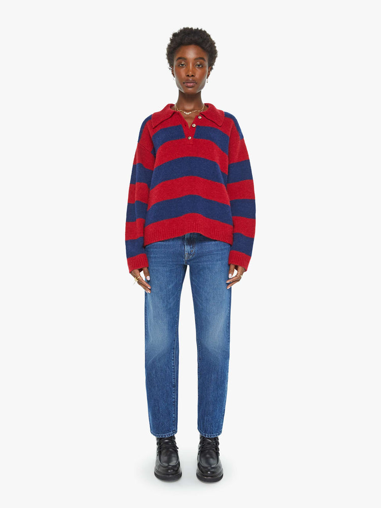 Full body view of a woman in a blue and red sweater stripes drop shoulders, a buttoned V-neck, ribbed hems and a loose, boxy fit.