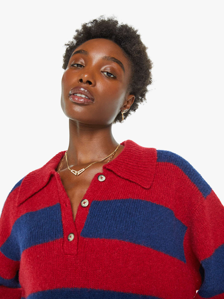 Close up view of a woman in a blue and red sweater stripes drop shoulders, a buttoned V-neck, ribbed hems and a loose, boxy fit.