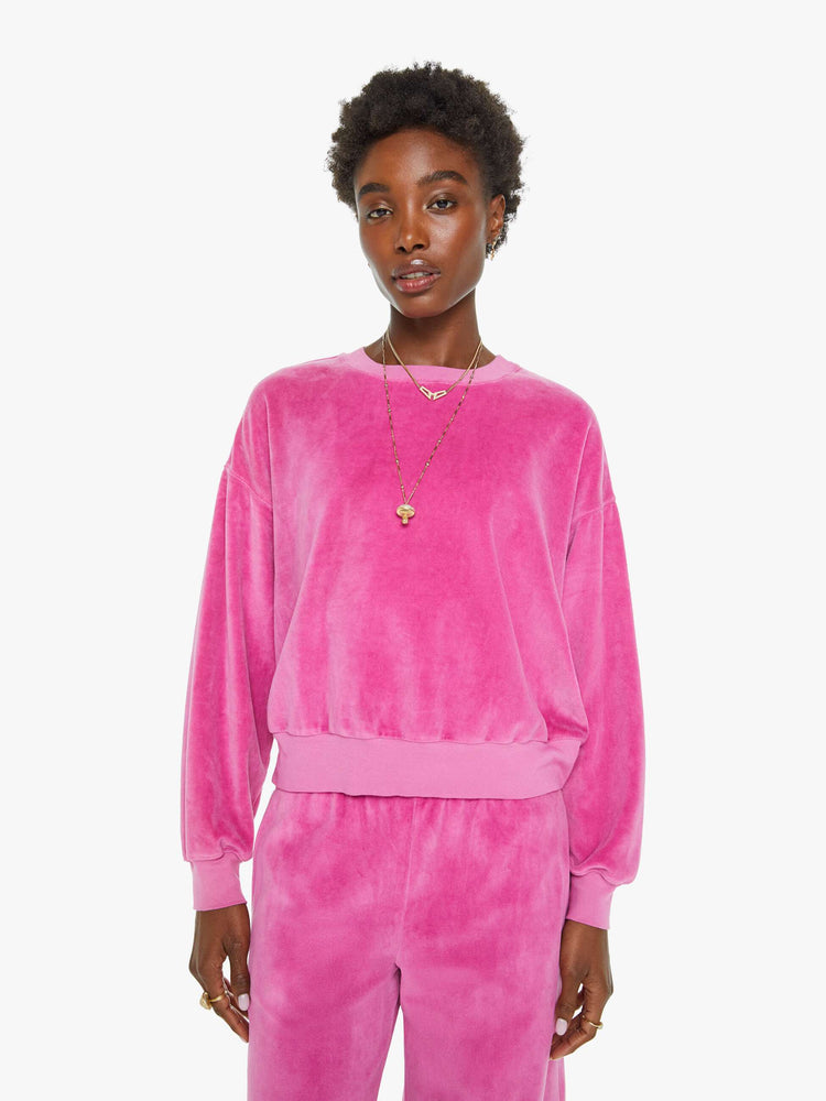 Front view of a woman in a pink velour sweatshirt features a crew neck, drop shoulders, ribbed hems and a slightly cropped fit.