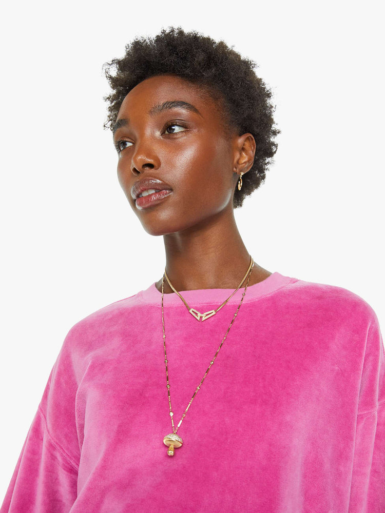 Close up view of a woman in a pink velour sweatshirt features a crew neck, drop shoulders, ribbed hems and a slightly cropped fit.